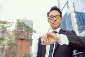 Businessman standing in street and looking at his watch