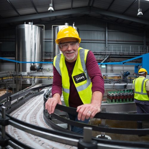 Portrait of smiling factory worker leaning on production line