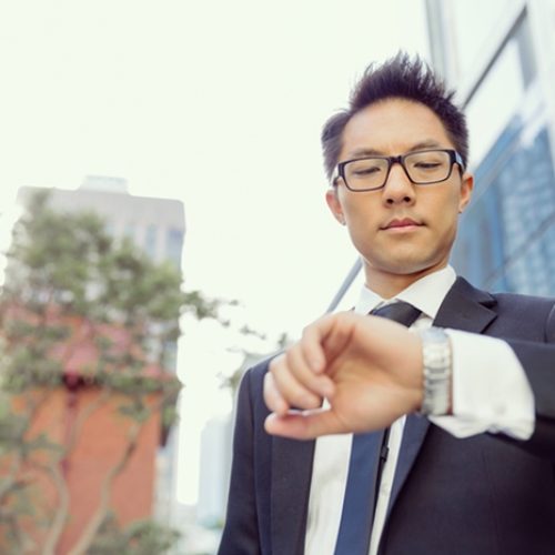 Businessman standing in street and looking at his watch